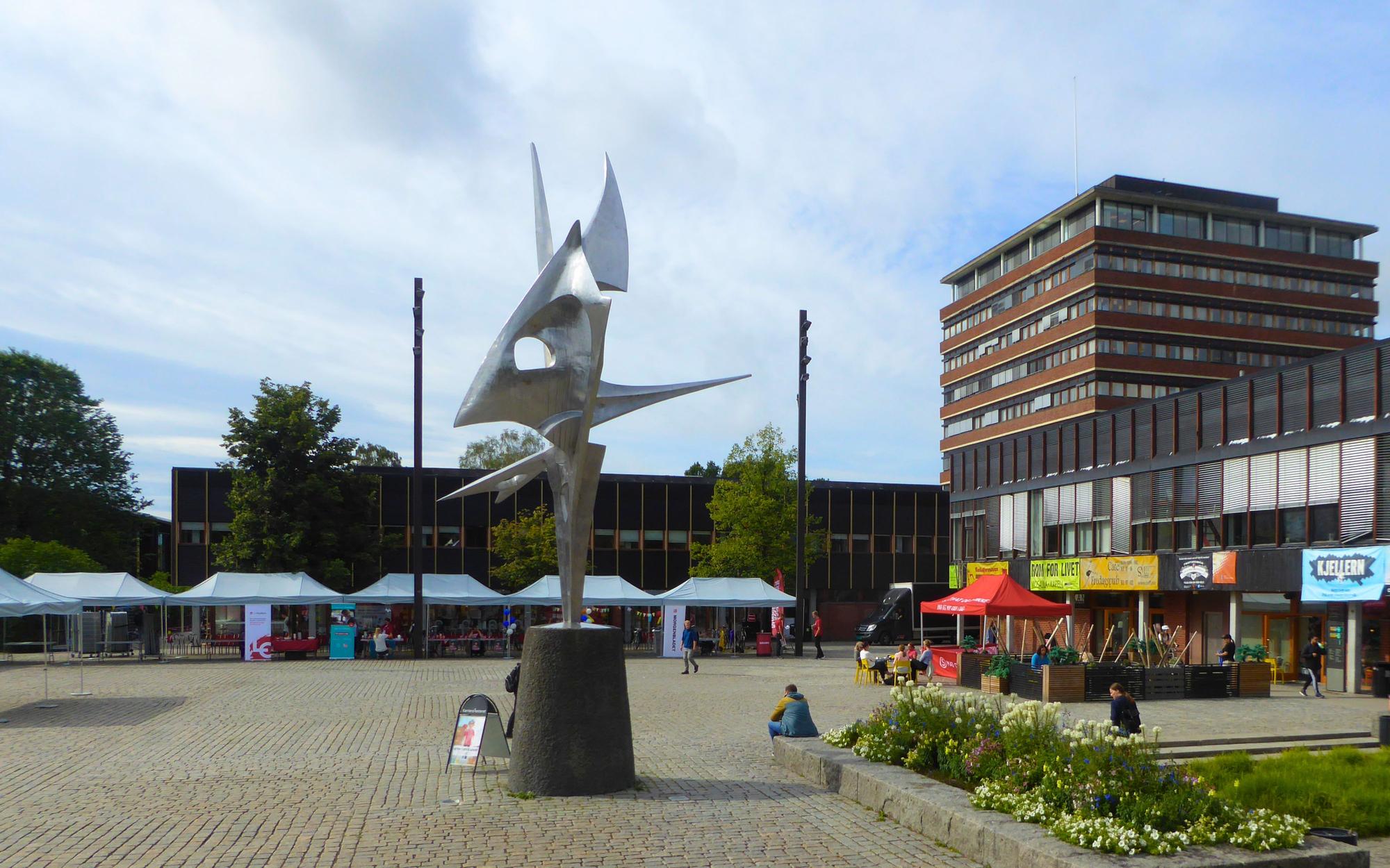 En statue på et torg, foran en bygning.