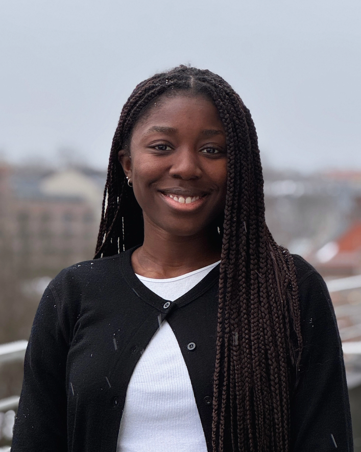 a woman wearing a black cardigan and a white shirt smiles for the camera