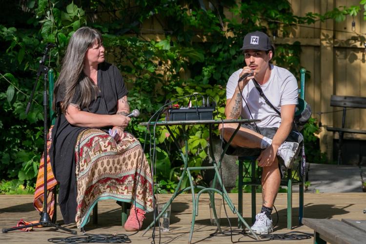 a man and a woman are sitting at a table talking into microphones .