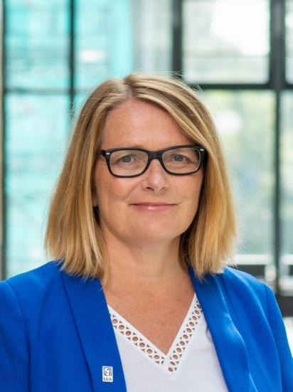 a woman wearing glasses and a blue jacket has a badge on her shirt that says ecl