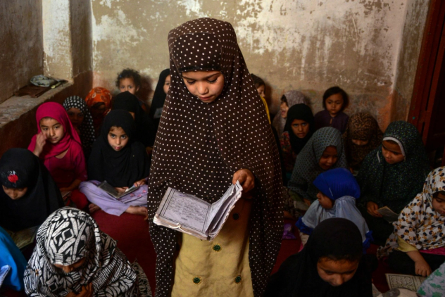 En ung jente i hijab leser fra en bok.