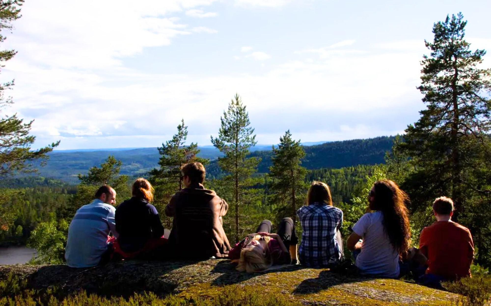 A group of people are sitting on a rock overlooking a forest.