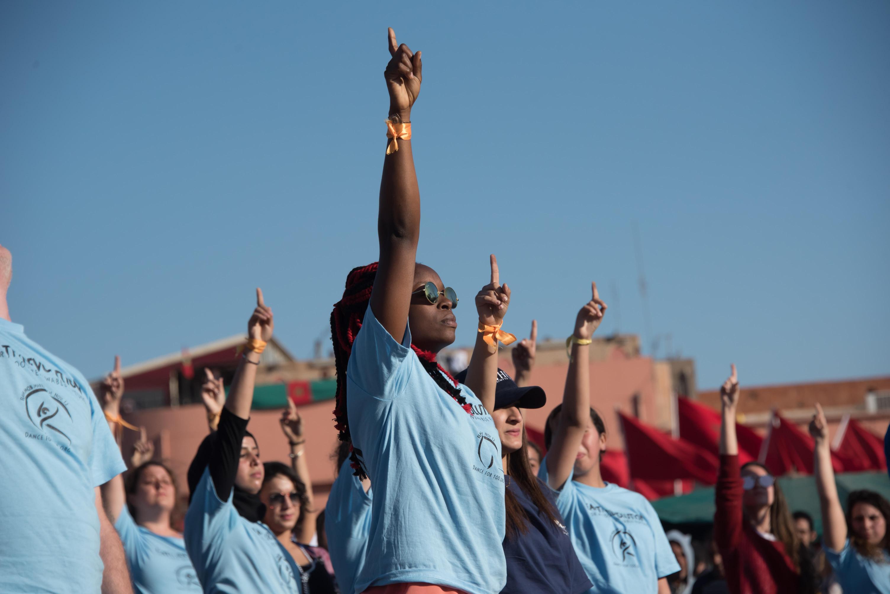 a group of people are standing in a line with their hands in the air .