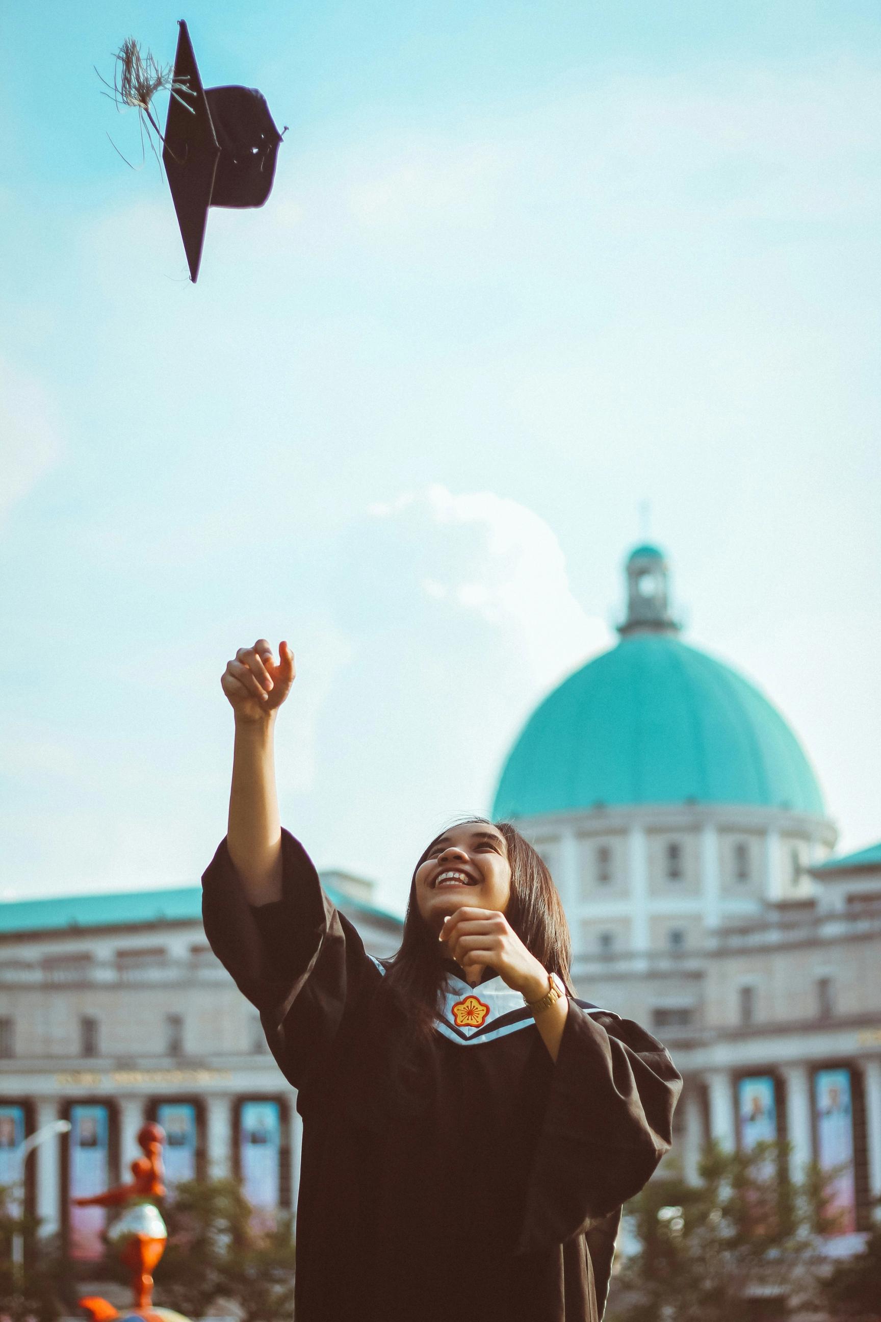 a woman in a graduation cap and gown is throwing her cap in the air .