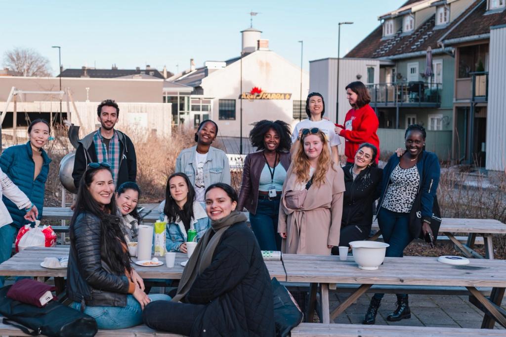 En gruppe studenter som nyter et måltid sammen ved et piknikbord utendørs.