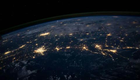 Earth from space at night, showing city lights across land.