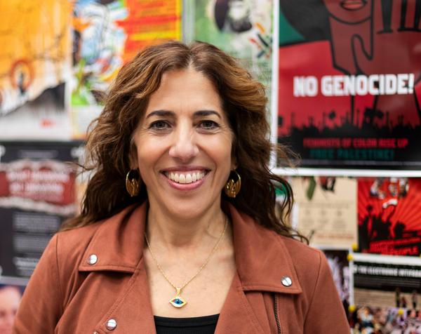 a woman is smiling in front of a wall of posters .