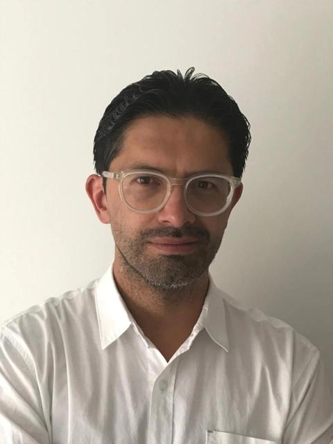 a man wearing glasses and a white shirt looks at the camera