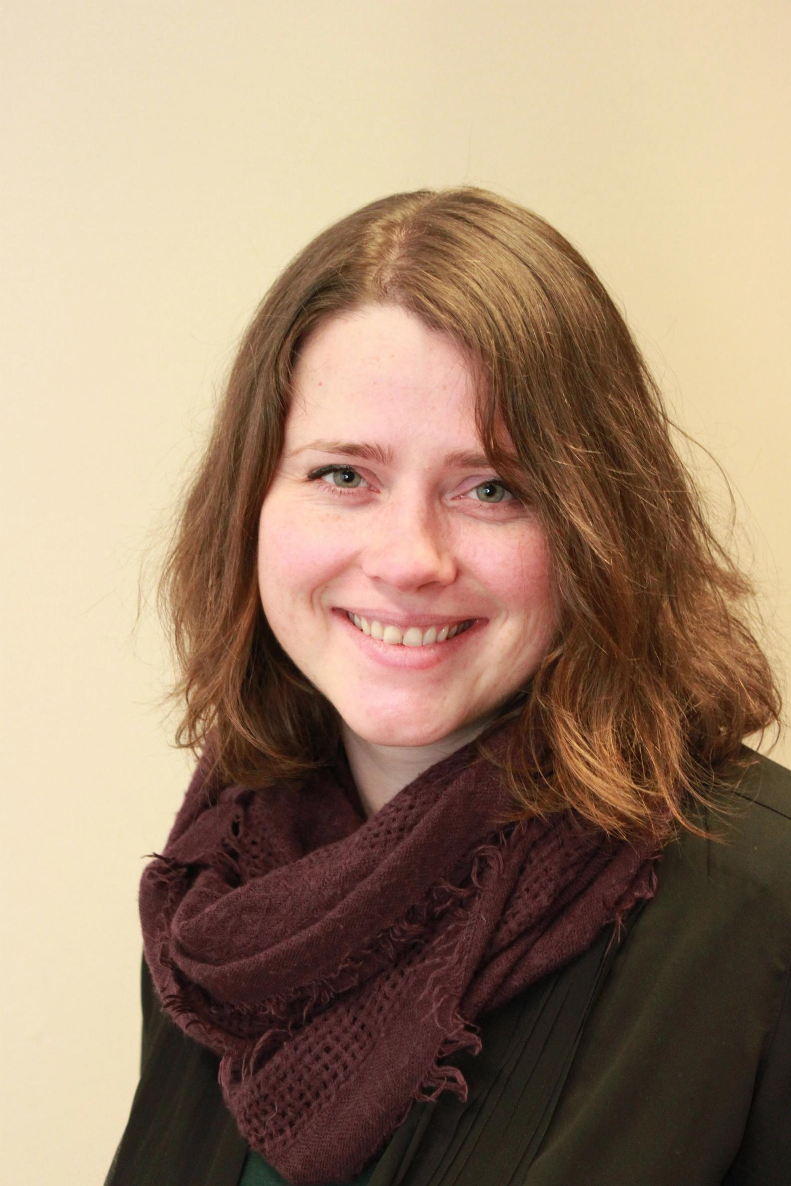 a woman wearing a purple scarf smiles for the camera