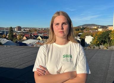 ung kvinne står med armene i kryss og ser alvorlig inn i kamera