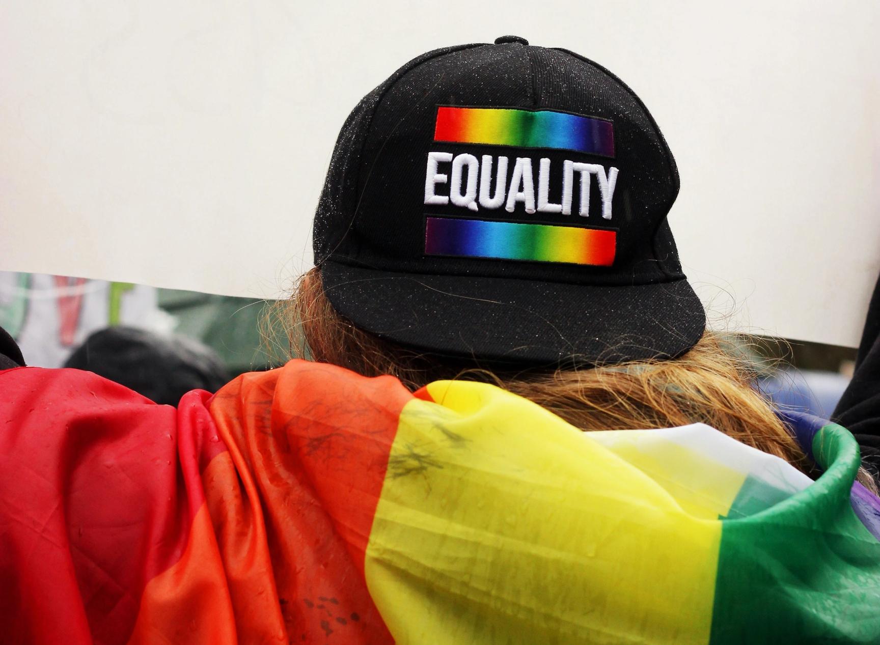 A person with an LGBT flag over his back and a cap with the text "equality".