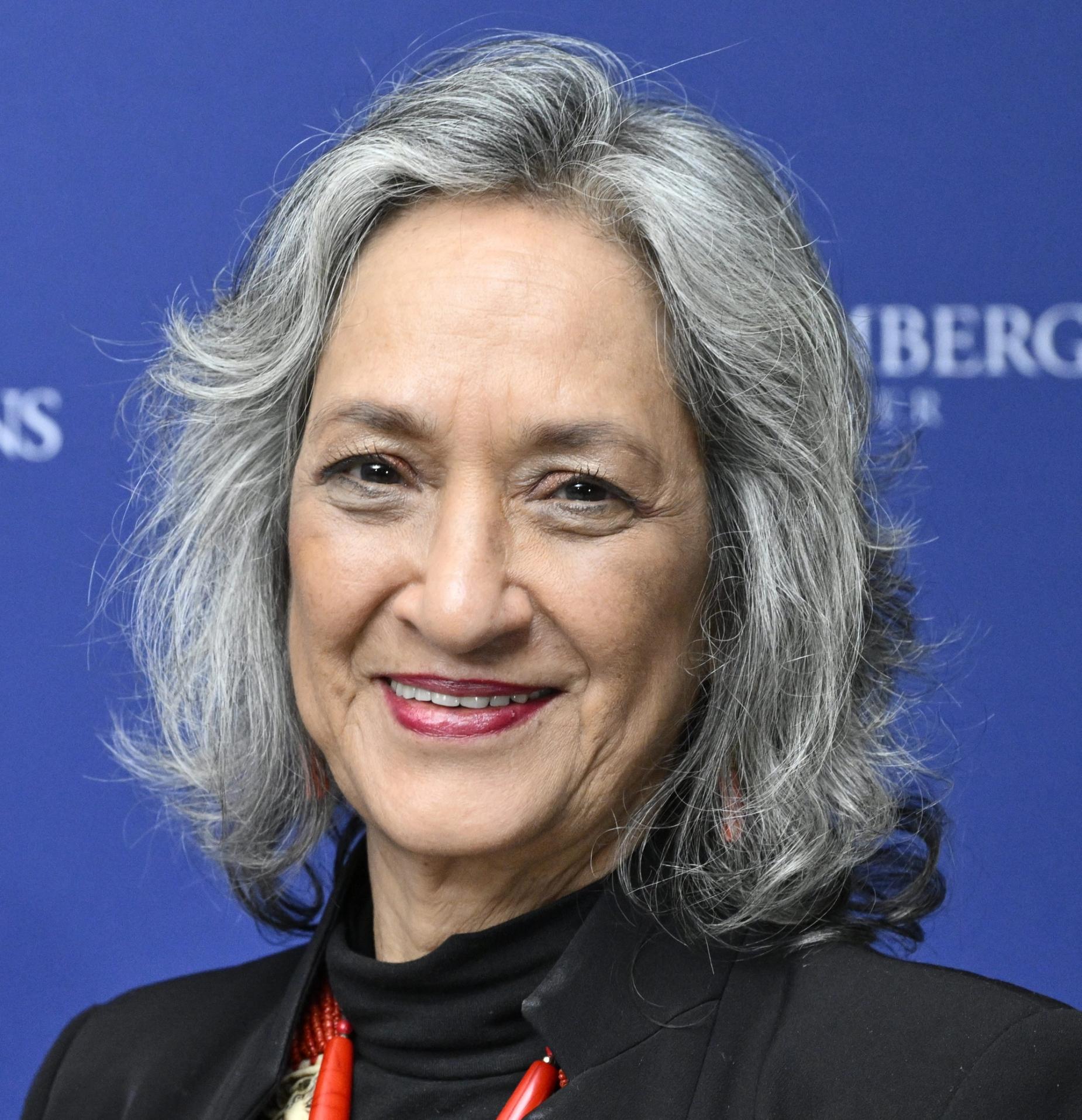 a woman with gray hair is smiling in front of a blue background .