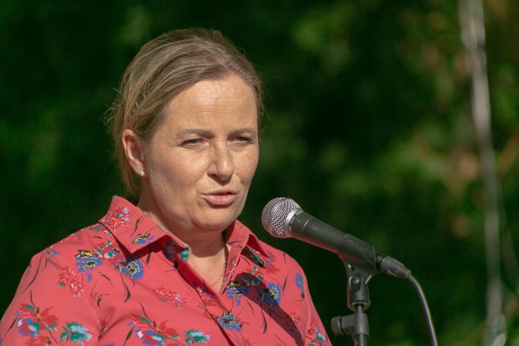 a woman in a red shirt is standing in front of a microphone .
