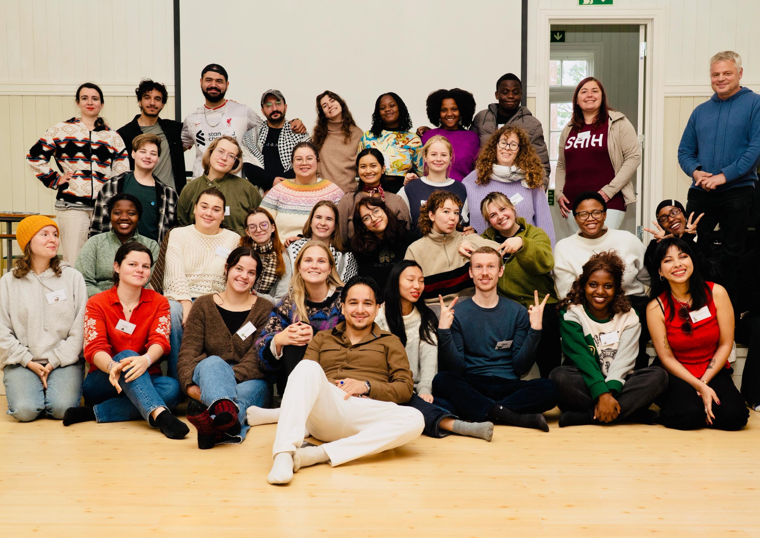 A large, diverse group of smiling people posing for a photo indoors.