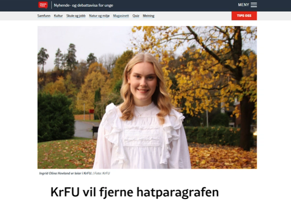 Smiling young woman in a white blouse standing in front of autumn trees.