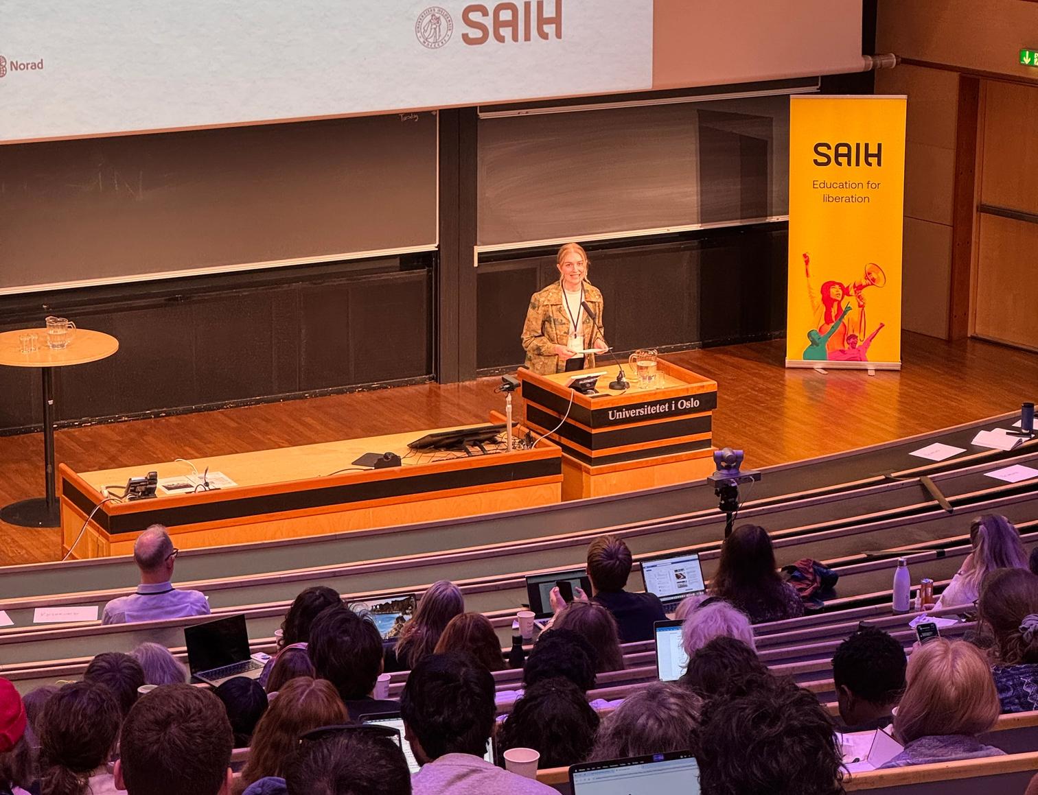 a woman is giving a lecture to a large group of people in an auditorium .