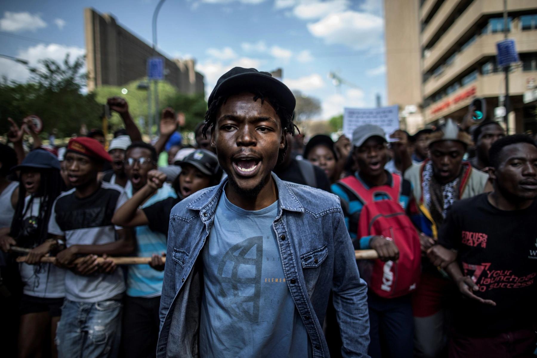 a man in a denim jacket is standing in front of a crowd of people .