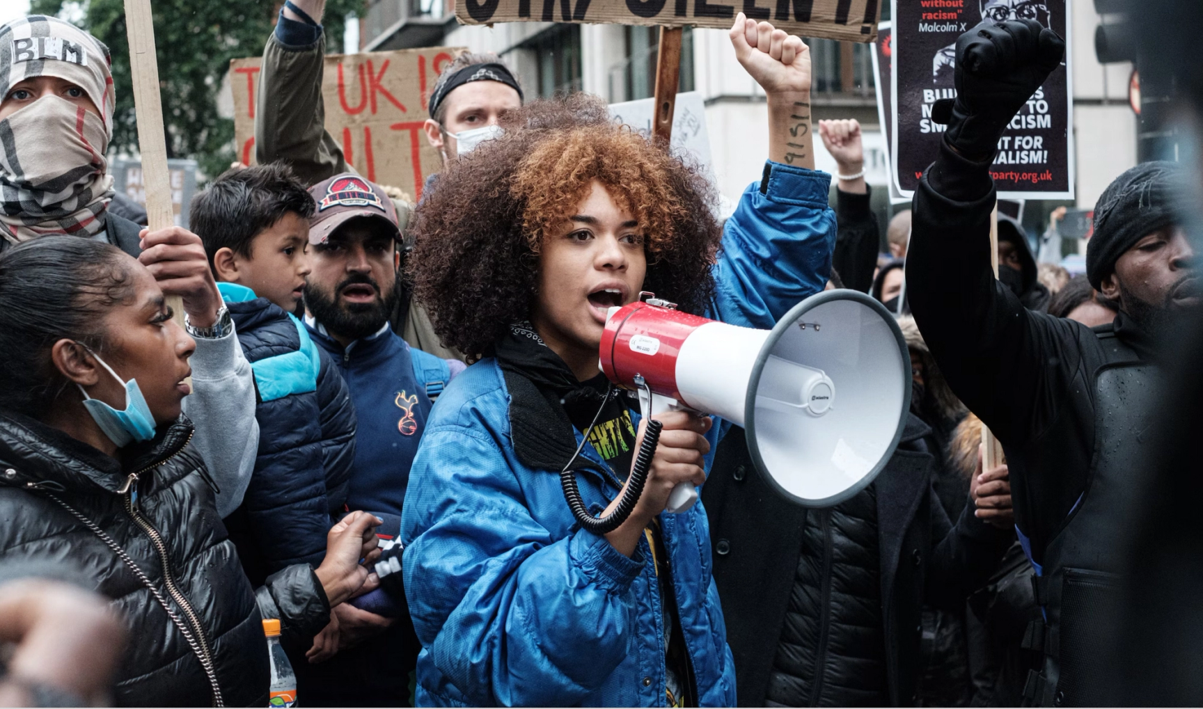 A woman holding a megaphone in front of a crowd.