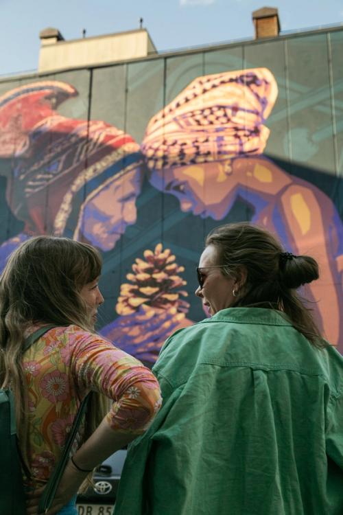 two women standing in front of a mural 