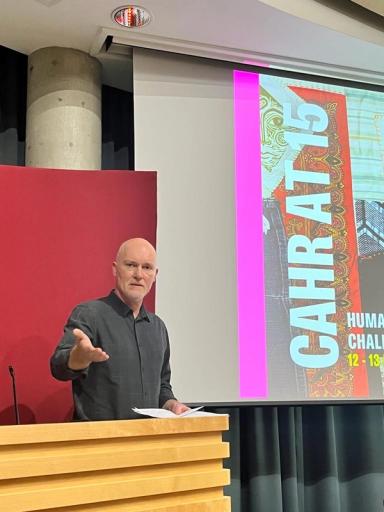 a man stands at a podium in front of a screen that says cahra 15