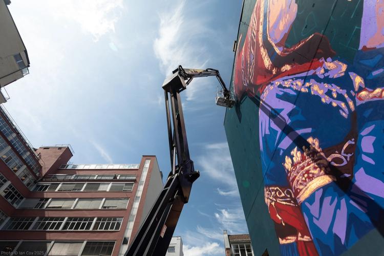 a large mural is being painted on the side of a building .