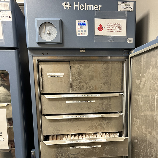 A refrigerator in a veterinary blood bank holding labeled blood bags.