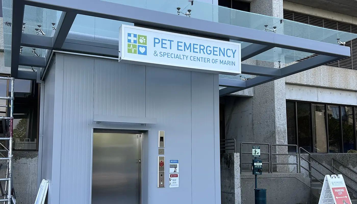 Sign for Pet Emergency and Specialty Center of Marin hung above a silver elevator on a building exterior.