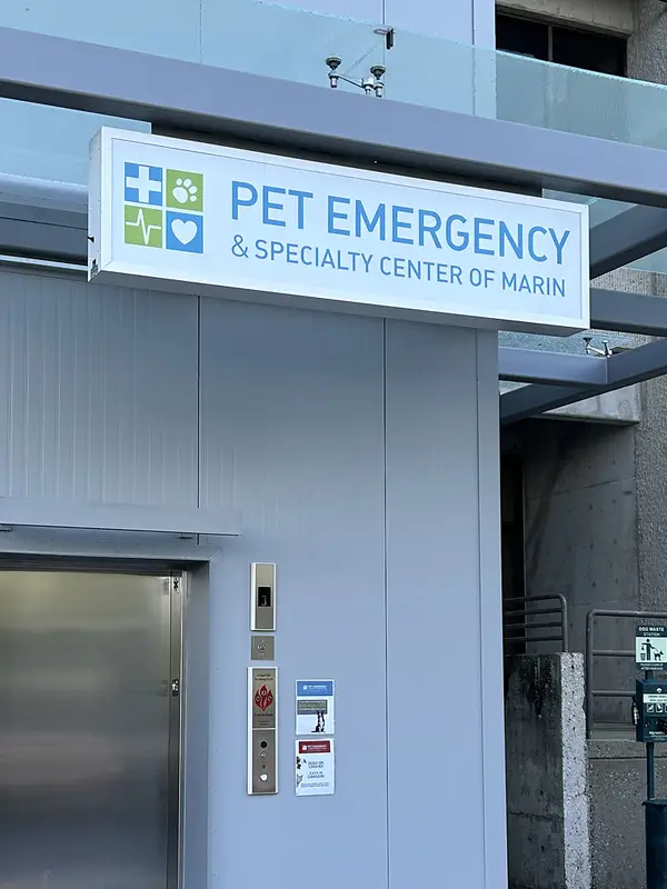 Sign for Pet Emergency and Specialty Center of Marin hung above a silver elevator on a building exterior.