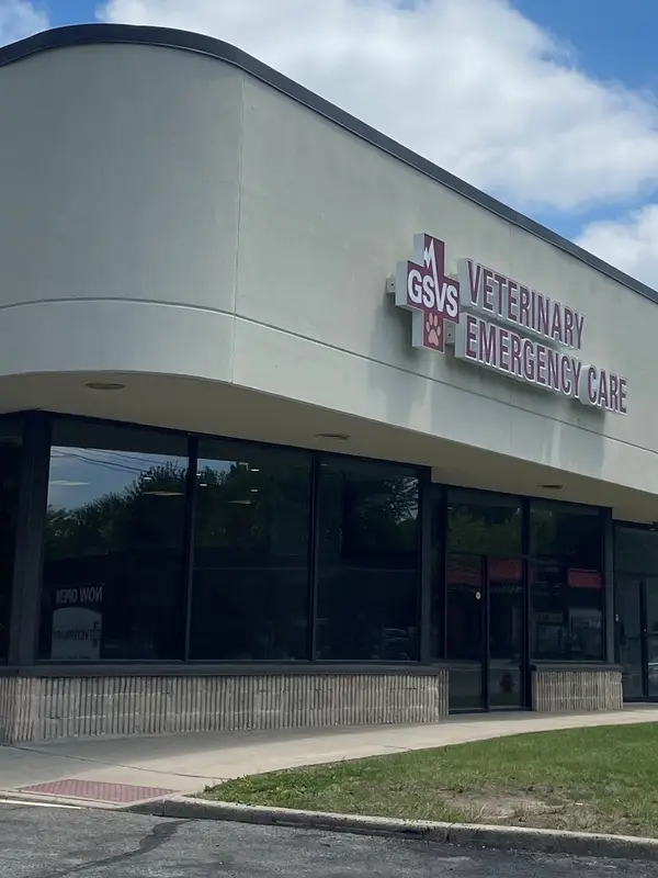 Corner exterior of a veterinary emergency care building with "Now Open" signage on the front lawn.