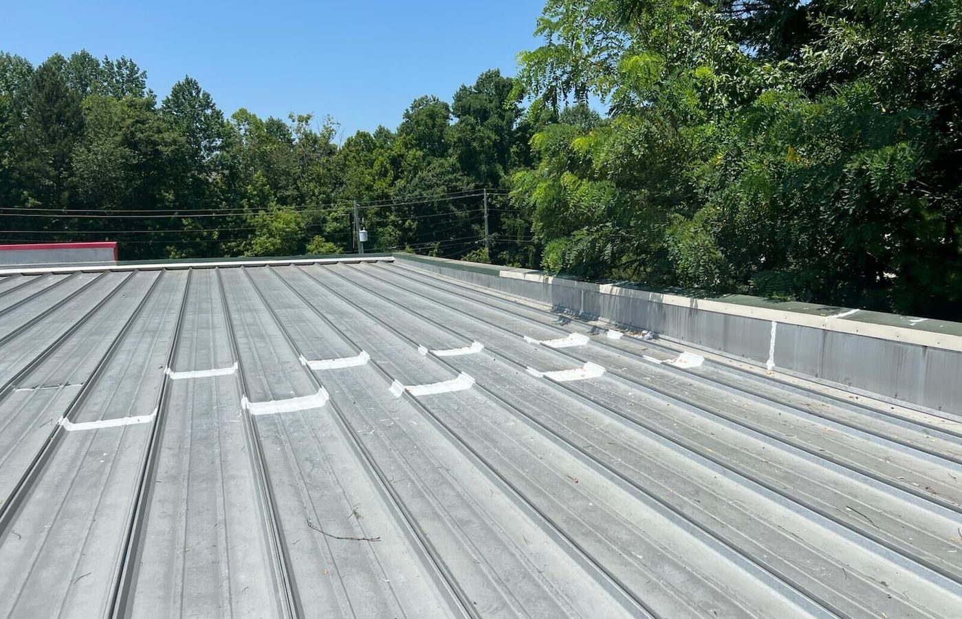 Metal roof with repaired field seams coated in white silicone