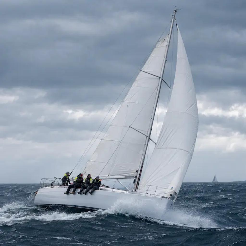 Crew sitting on the rail of a racing sailboat during an offshore race