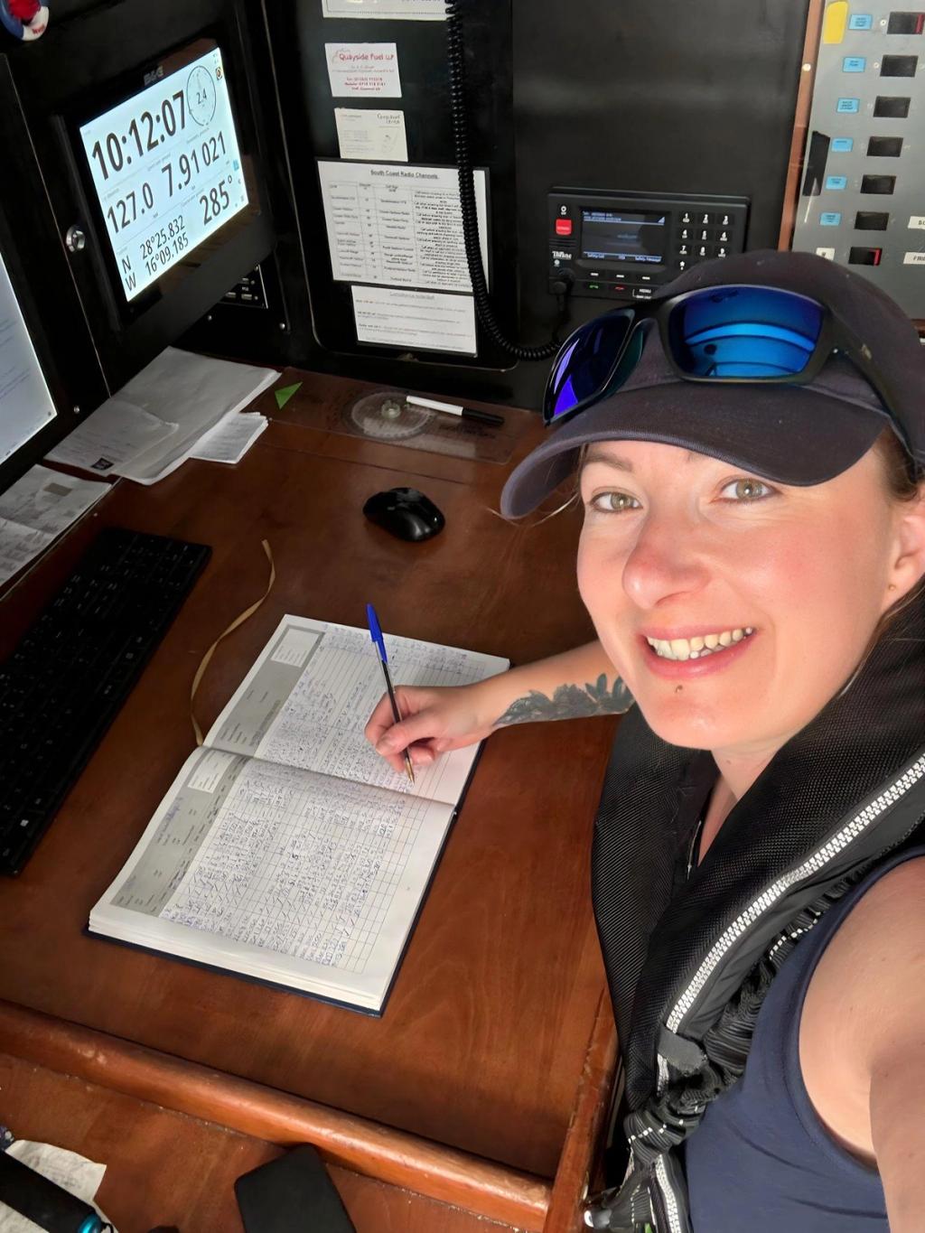 Elouise writing up the ship's log at the nav station