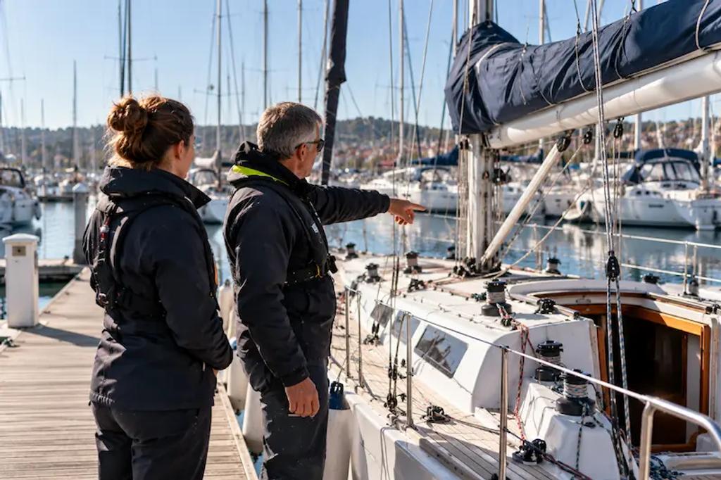 Skipper briefing a new crew member on the pontoon before a sailing trip