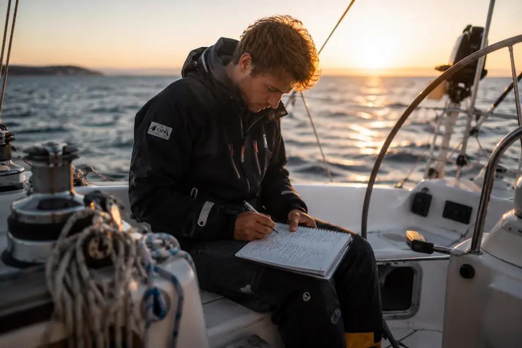 Sailor logging sea time in a sailing logbook after completing sailing school