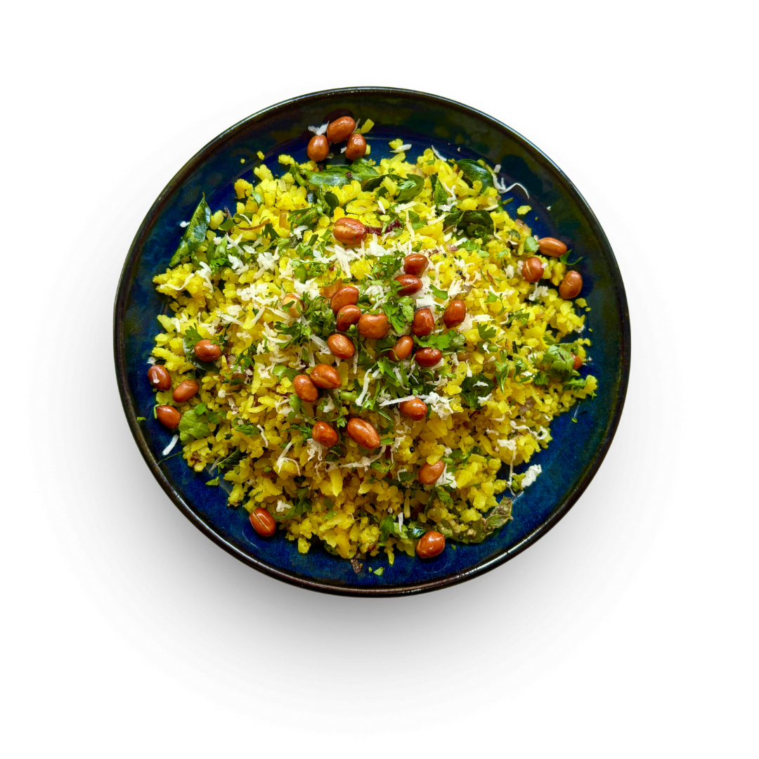 Maharashtrian-style kanda poha with peanuts, shredded coconut, coriander, and mustard seeds, served on a blue ceramic plate.