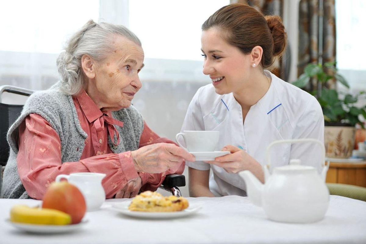 Cuidadora oferecendo refeição nutritiva ao idoso