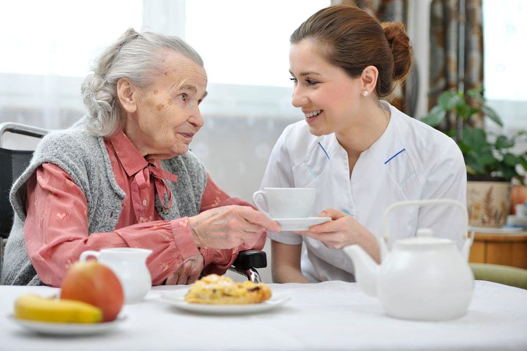 Cuidadora oferecendo refeição nutritiva ao idoso