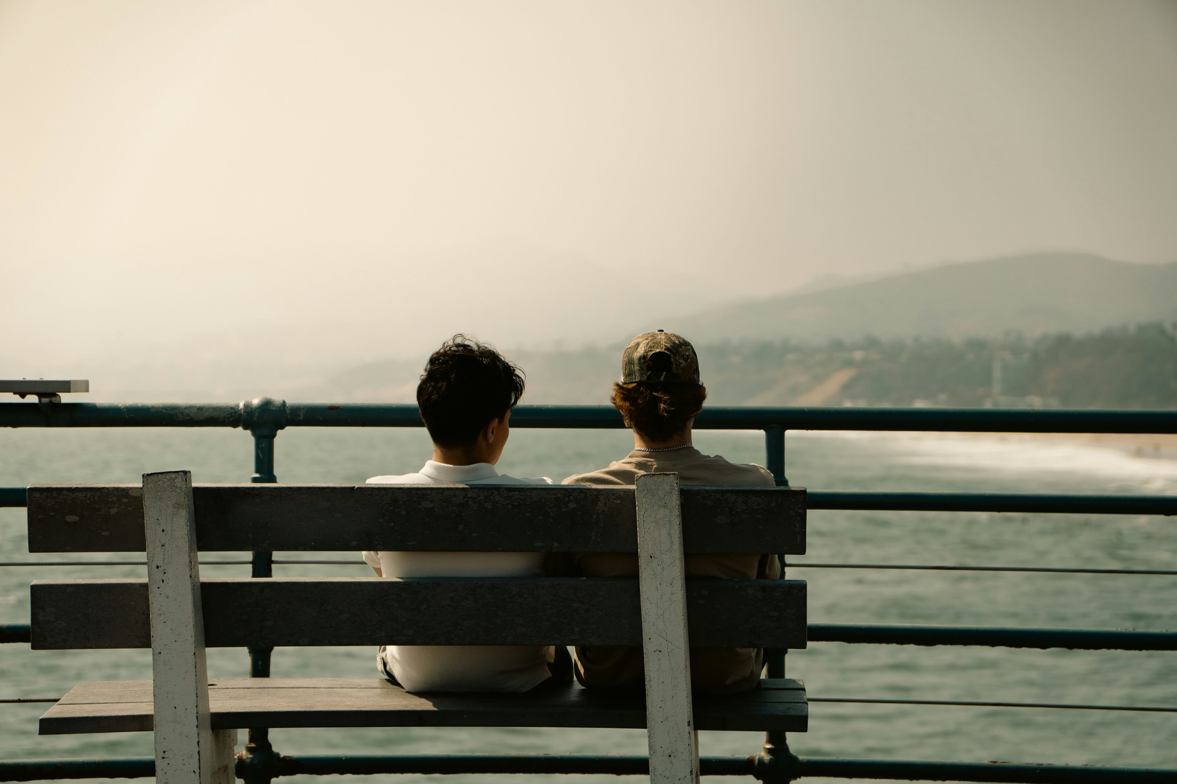 couple sitting on bench looking at the ocean