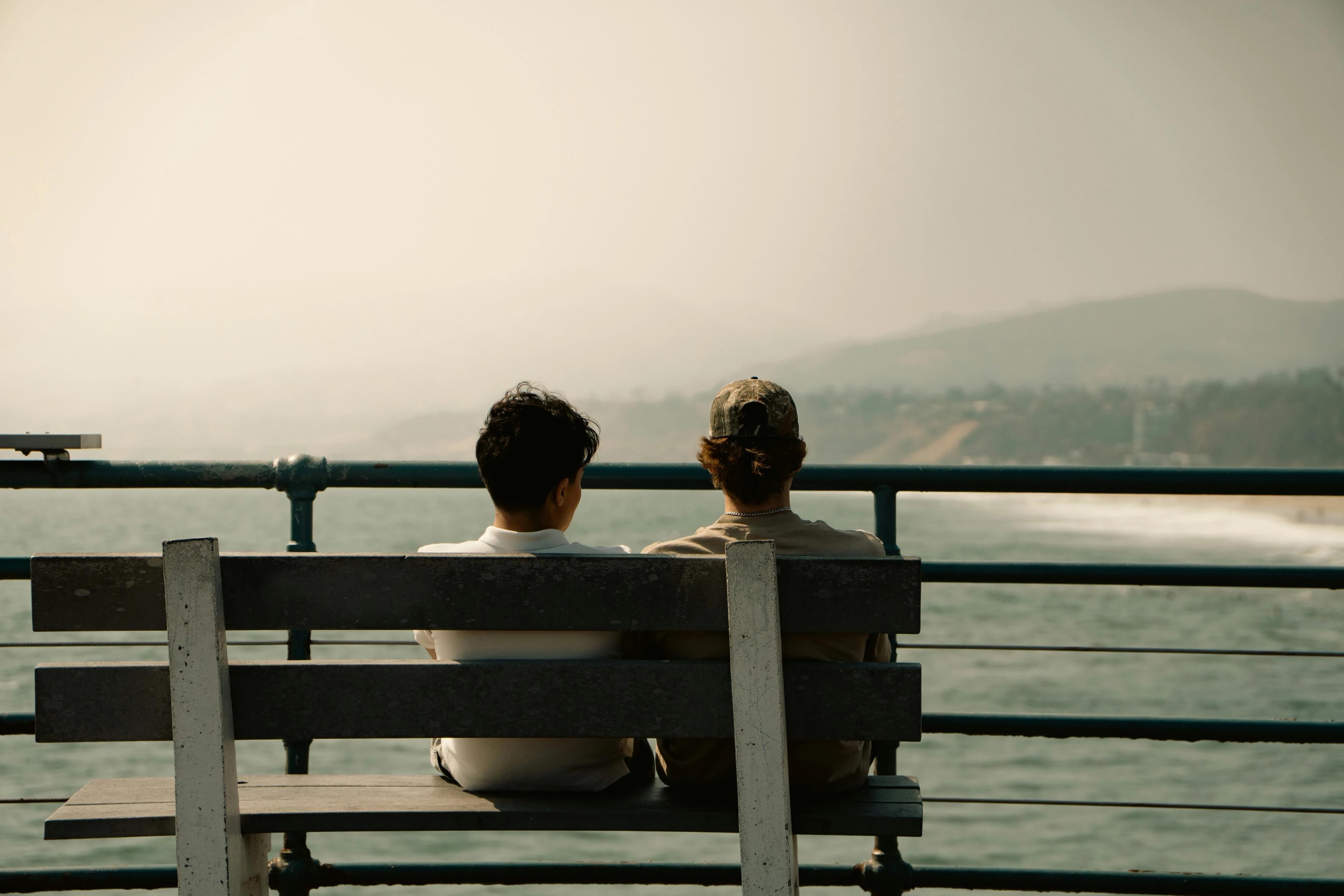 couple sitting on bench looking at ocean