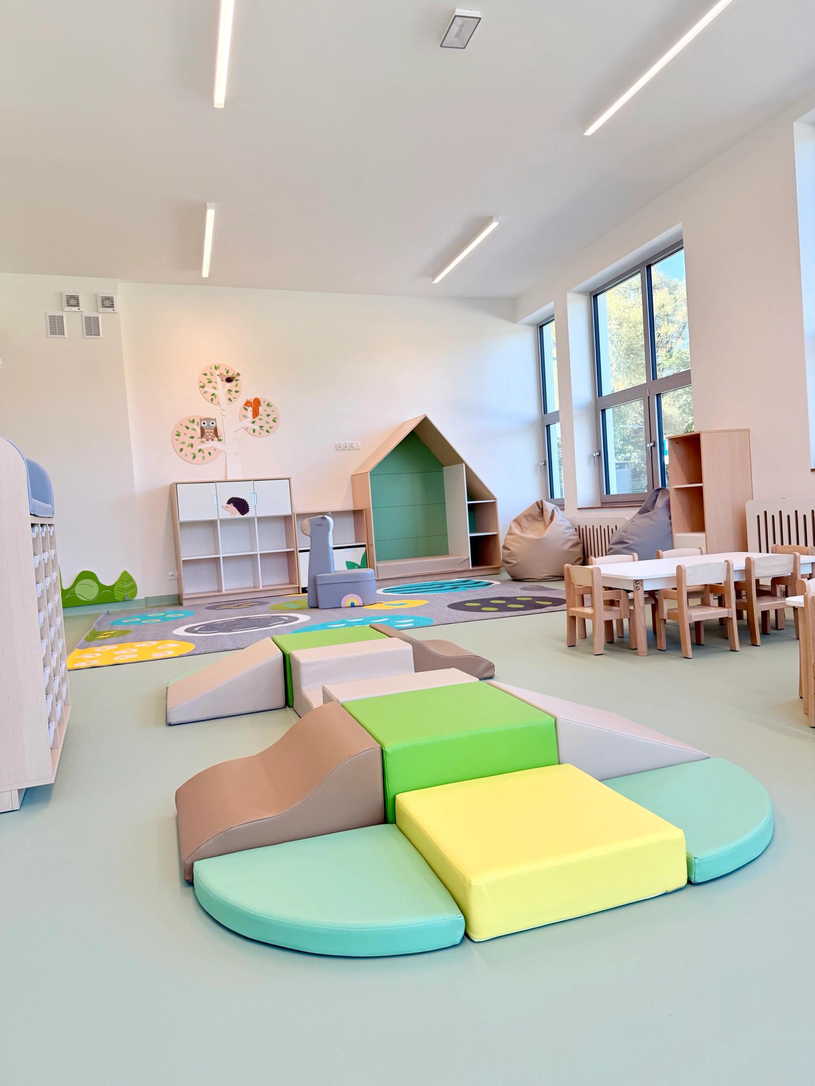 Sala Kolorowych Marzeń — przestronna sala z miękkimi klockami, kolorowym dywanem, drewnianym domkiem i stolikami przy oknach