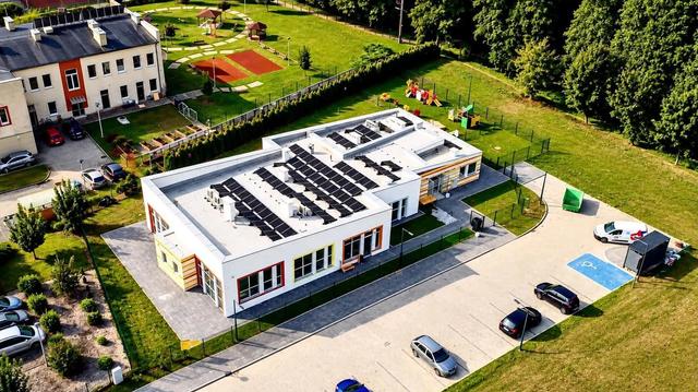Budynek żłobka z lotu ptaka, obok plac zabaw i parking