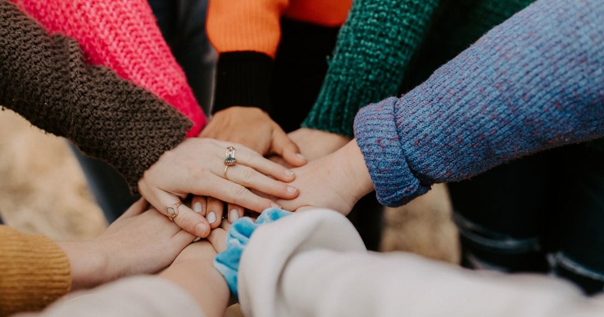 group stacking hands in colorful sweaters