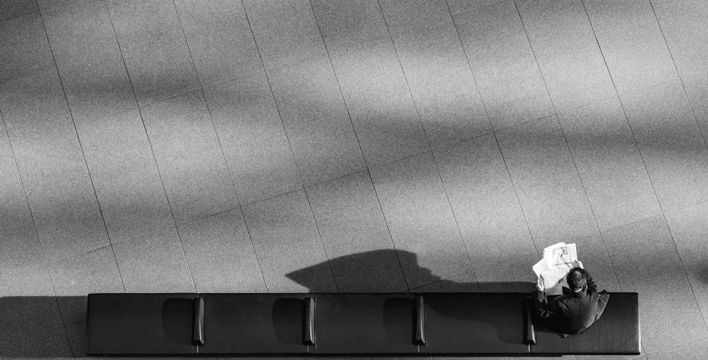 Lone figure waiting on an empty bench in long shadow, illustrating the hidden cost of free survey tools