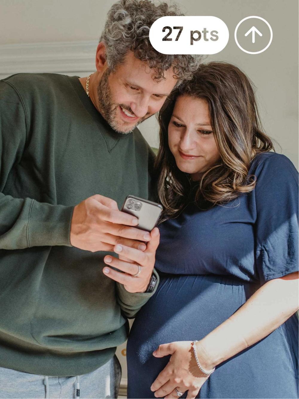 Millennial couple expecting a child looking at the man's credit scores in the KOHO app