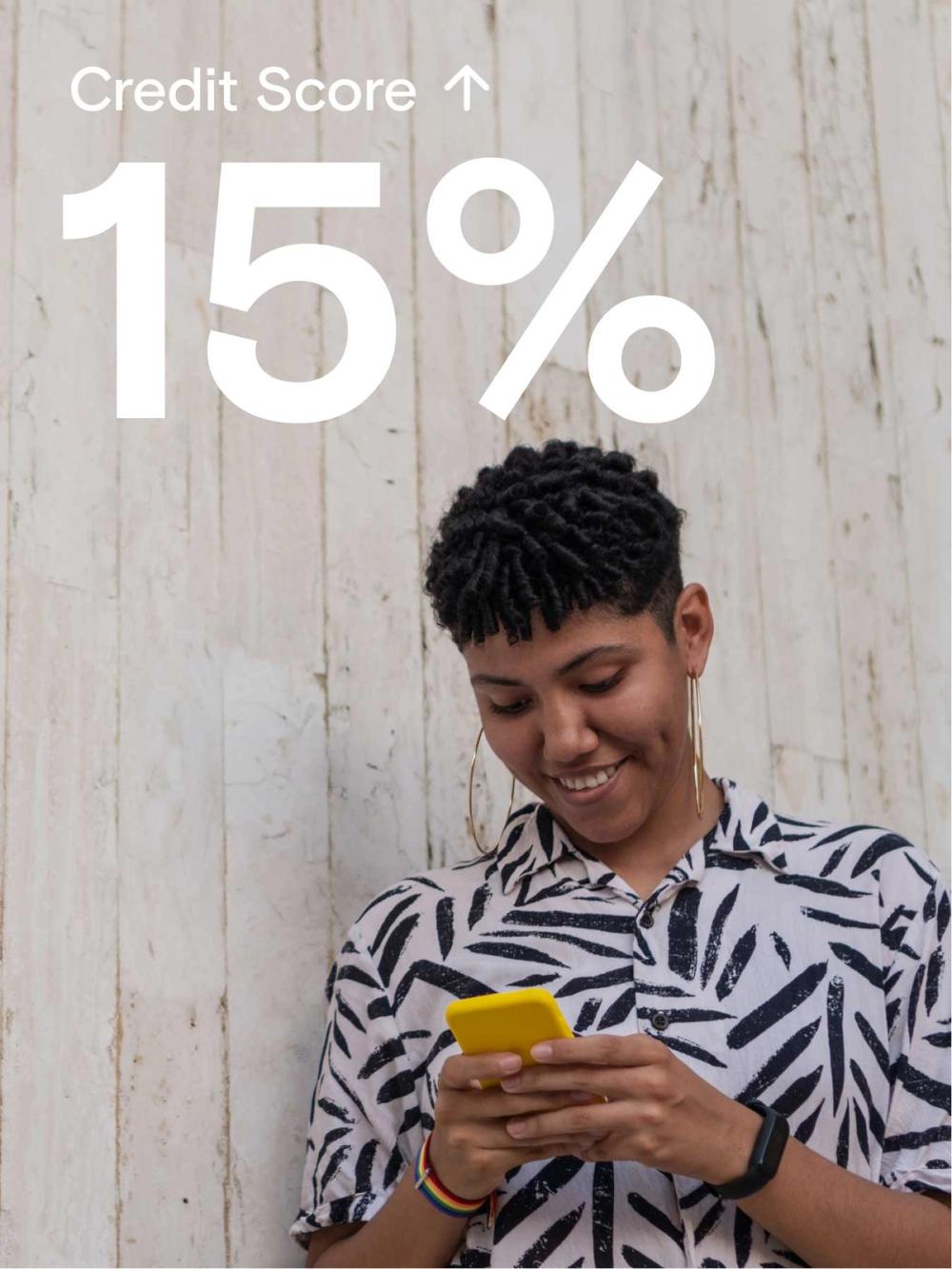 Young person looking at their phone smiling because their credit scores went up 15% thanks to KOHO