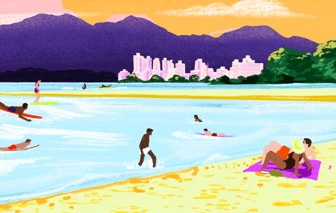 People on the beach, next to a city and mountains.