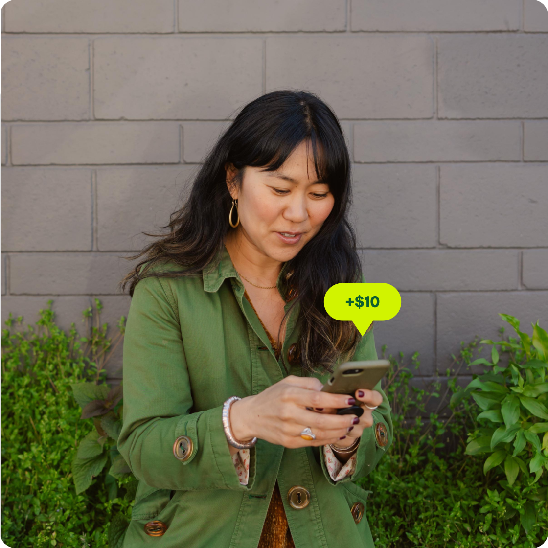 Une femme regarde son téléphone pour voir les remises en argent qu'elle a obtenues sur son loyer.