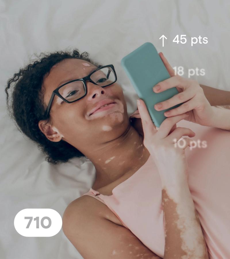 A woman lying in bed happy to see her credit scores increase thanks to KOHO's Credit Building