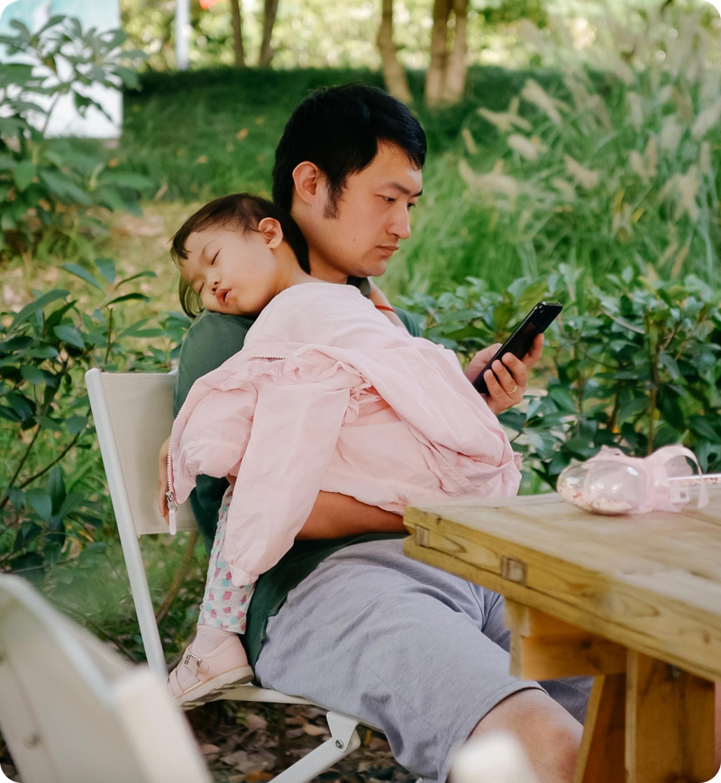 Father holding a child and on their phone 