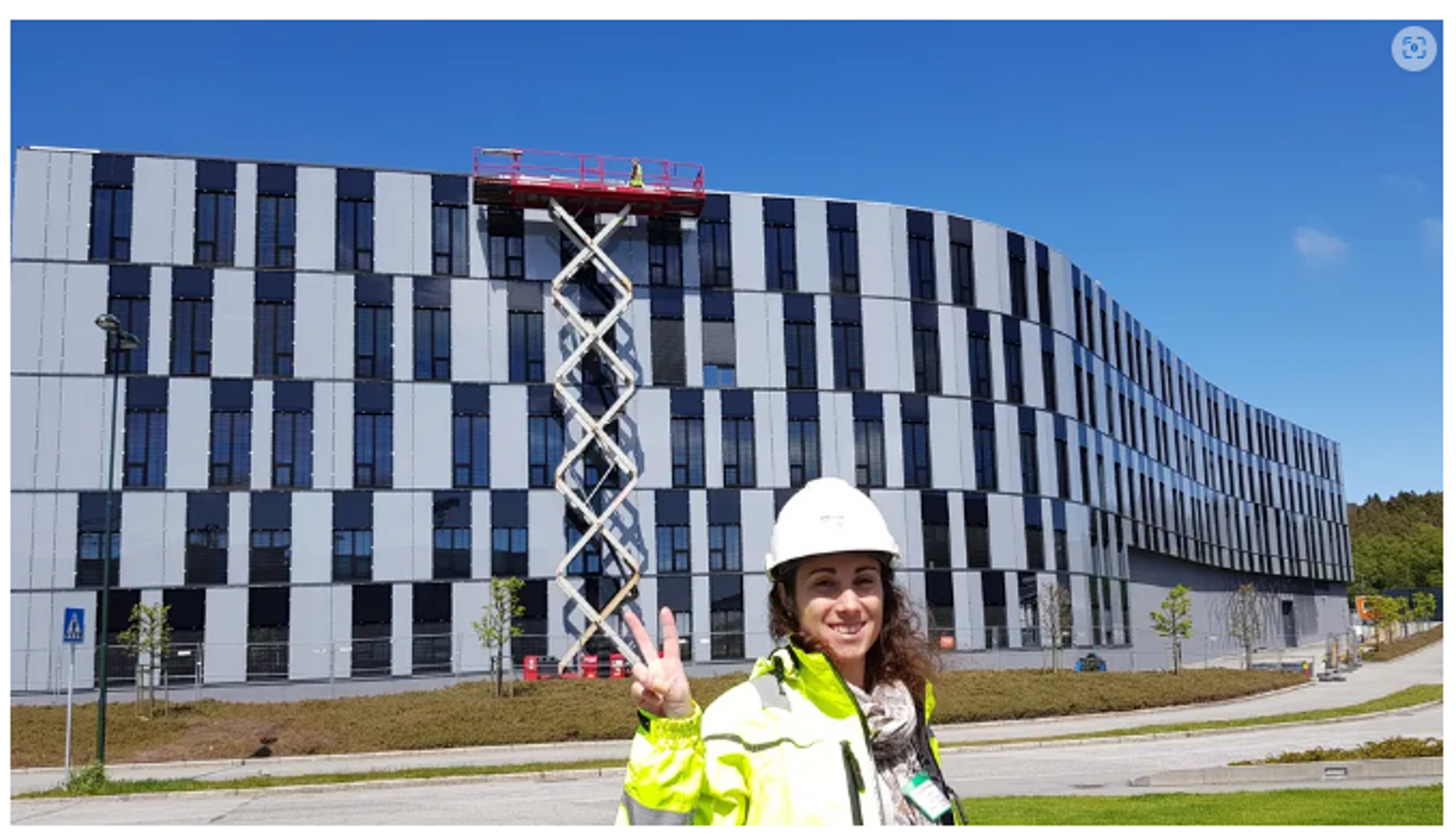 Woman construction worker standing in front of a commercial building with solar panels